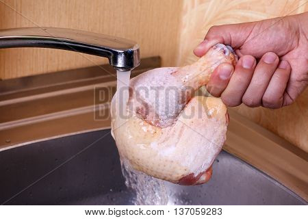 Frozen chicken leg in hand running water