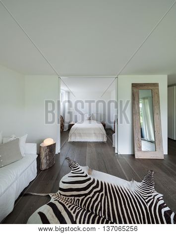living room with bedroom view, leather zebra on the floor, white walls