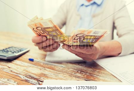 business, savings, annuity insurance, age and people concept - close up of senior woman with calculator and bills counting euro money at home
