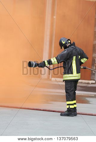 Fireman With An Extinguisher Under The Orange Smoke