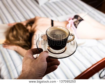 beautiful woman reading a thick book lying on the bed, close-up coffee cup.