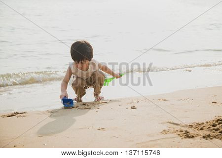 Cute asian boy playing on the beach