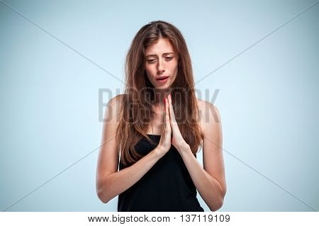 The woman with long red hair is looking imploring over gray background