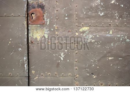 Metal door with mortise lock on rusty surface with old paint stains on metallized background