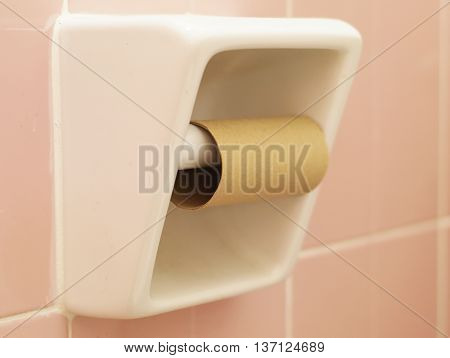 White ceramic tissue paper holder with empty tissue paper and pink tile in the background