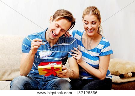 Happy couple - woman hugging her husband who holding gift box and baby shoe