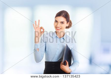 Happy smiling beautiful young businesswoman showing okay gesture. With blank copyspace area for text or slogan.