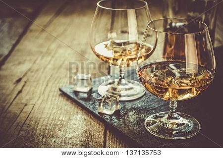 Cognac in glasses on rustic backgrpund, copy space, toned