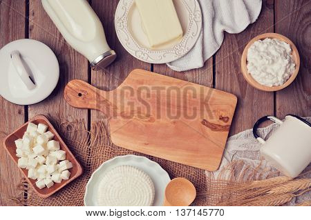 Milk cheese and butter with cutting board on wooden background. View from above. Flat lay