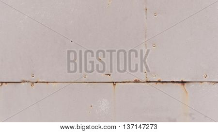 part of the gray rusty scratched metal gate covered with dark orange stains and rusty strips it is visually divided into three parts,