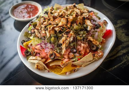 Colorful Mexican nachos with chicken black olives melted cheese jalapenos and more