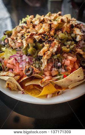 Colorful Mexican nachos with chicken black olives melted cheese jalapenos and more