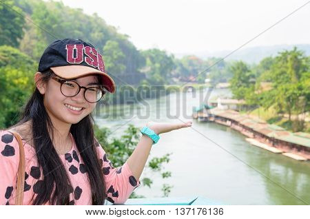 Tourist girl show hands invites to visit beautiful landscape of Death Railway bridge over the Kwai Noi River at Krasae cave viewpoint in Kanchanaburi province Thailand
