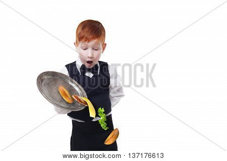 Clumsy little waiter drops food from tray serving hamburger. Cheeseburger falling with separated toppings. Dropping burger layers. Redhead child boy in suit failure, isolated at white background