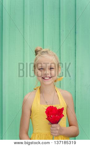 Cheerful young blond girl holding a red flower. Space for text