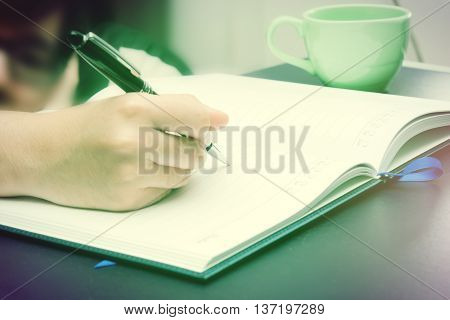 Write activity (A girl hand holds a pen and write on a book) with morning lighting