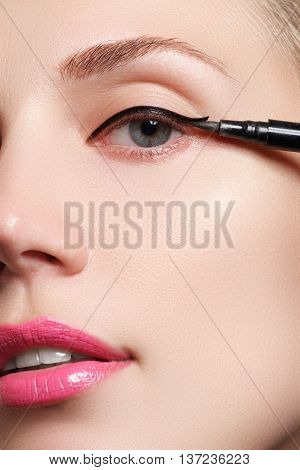 Woman make-up applying close-up. Eyeliner. Cosmetic eyeshadows. Eyeline brush for make-up. Beauty girl with perfect skin. Eyelashes. Blue eyes. Makeover