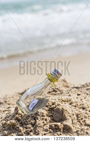 SOS message in glass bottle on the beach.