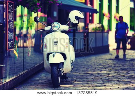 White scooter and what a summer cafe in the street paving of the old Riga
