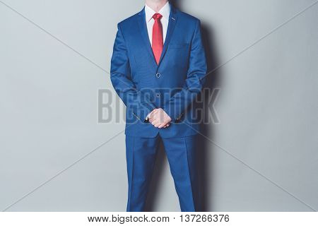 Portrait of successful businessman wearing blue siut and red tie against gray background
