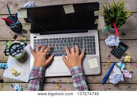 Overhead shot of messy office desk with modern laptop