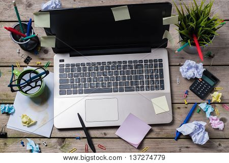Overhead shot of messy office desk with modern laptop