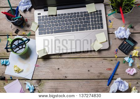 Overhead shot of messy office desk with modern laptop