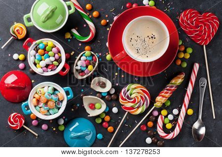 Colorful candies and coffee cup on stone background. Top view
