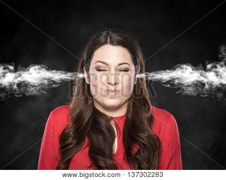 Smoke from the ears of a woman on a dark background. Overvoltage - concept.