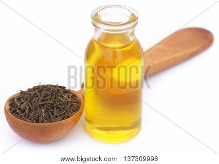 Caraway seeds in a wooden spoon with essential oil in glass bottle