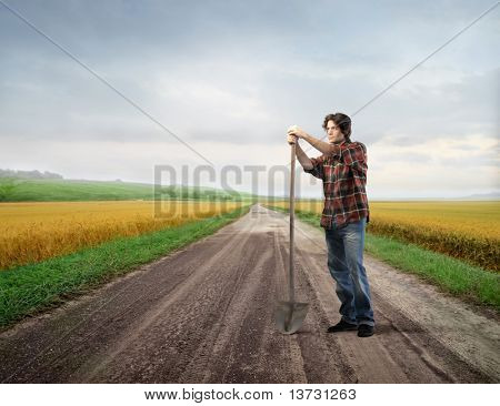 Mladý farmář drží lopatu s poli na pozadí