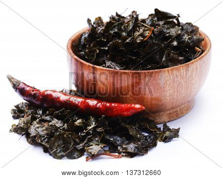 Fried moringa leaves in a bowl over white background