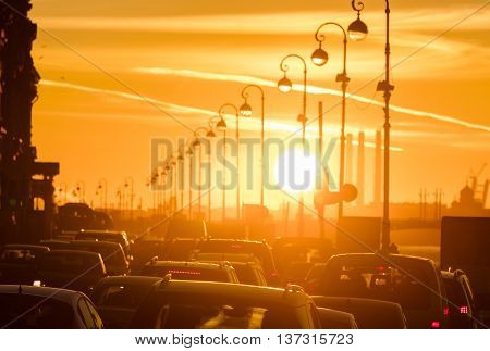 Cars are in a traffic jam during a beautiful golden sunset in a big city.