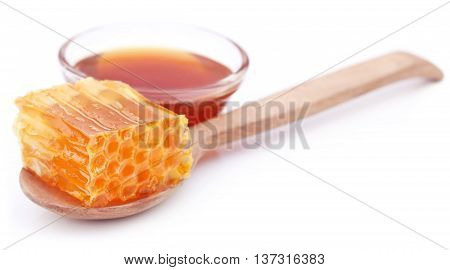 Honey comb with honey in a glass bowl over white background