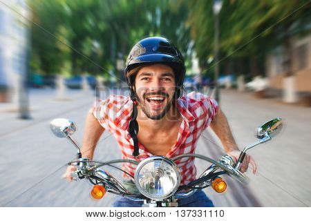 Smiling handsome young man riding white scooter. Motion blurred concept.