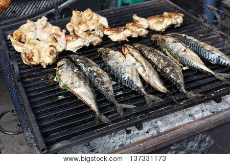 Plenty of chicken tabaka and fish grilled at barbecue. Mackerel bbq outdoors at picnic, party. Street food, roasted meat and seafood grill takeaway at grate