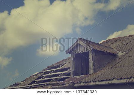 Old tile roof with holes and sky with clouds. Toned landscape.