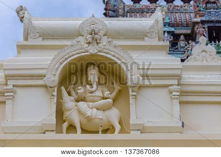 Tamil Nadu India - October 18 2013: Cream-colored Ganesha statue at Pillayarpatti Karpaga Vinayagar temple entrance. Ganesha sits on his mount the rat.