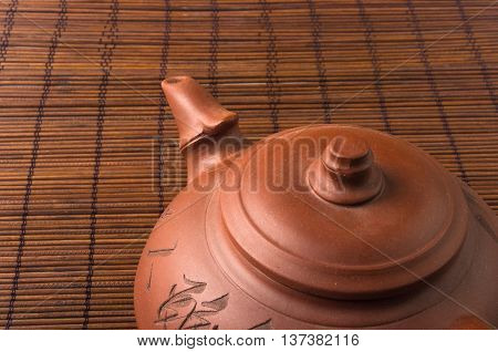brown Chinese teapot of Yixing clay with traditional ornament on bamboo Mat