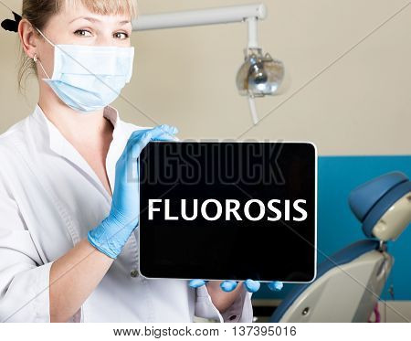 technology, internet and networking in medicine concept - femail dentist holding a tablet pc with fluorosis sign. at the dental equipment background.