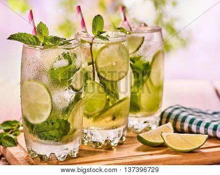 Alcohol drink. On wooden boards three glasses with alcohol drink and ice cubes. A drink number forty seven cocktail mohito with knife and mint leaf. Country life. Light background.