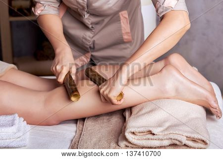 Woman having anti-stress massage with bamboo sticks. Spa Salon rejuvenating body massage