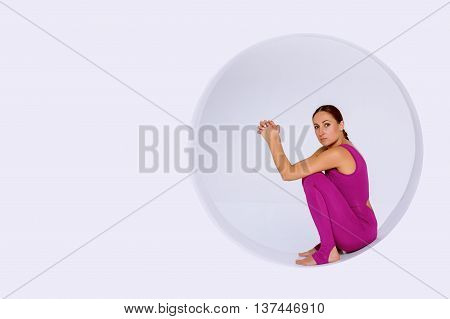 Beautiful and sporty woman in active wear sitting in geometric design of round shapesin sphere. Creative concept of sports Empty space for your text