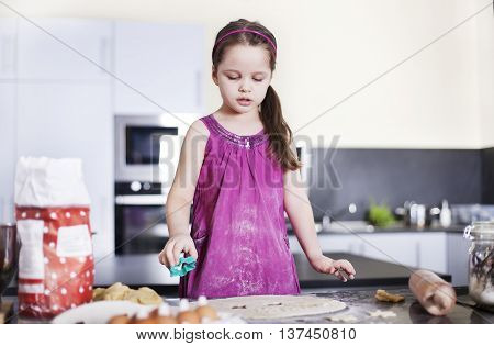 little daughter cooking in the kitchen at home. Girl Assisting In Preparing Food - Stock image