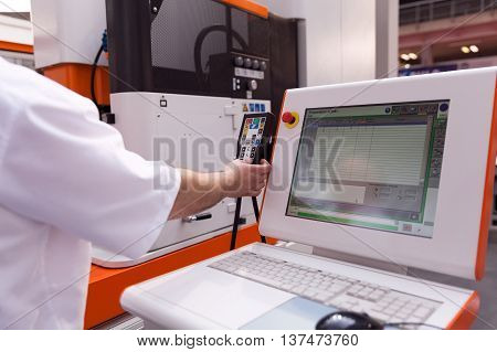 Technician working with computer numerical control (CNC) programmable machine. CNC technology.