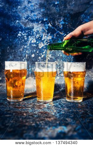 Close-up Of Barman Hand Pouring Beer From Bottle In Beer Glasses