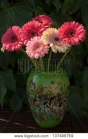 Colorful gerbera daisies in green vase made from mozaic murano glass