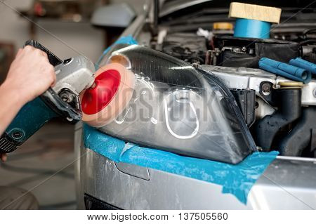 Auto Mechanic Enginner Polishing A Headlight Of A Modern Car Wit