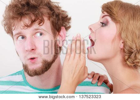 Closeup woman telling an astonished surprised man some secrets couple talking