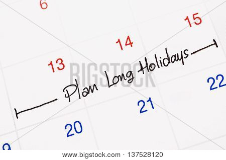 Plan long holidays word written on a white calendar page to remind.